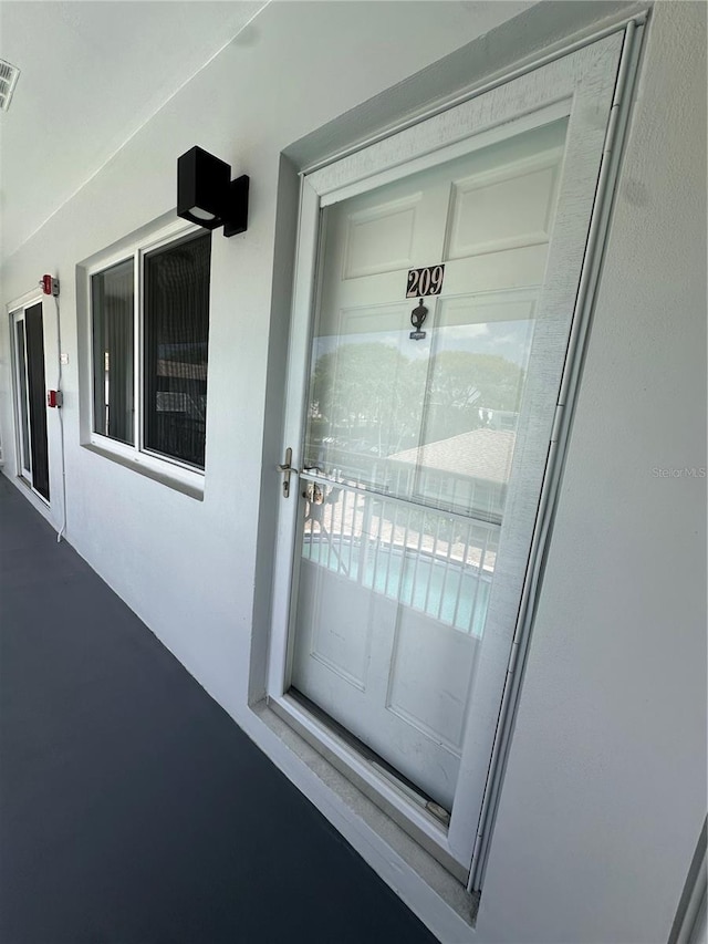 view of exterior entry with visible vents and stucco siding