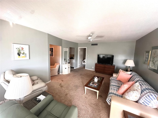 living room featuring a textured ceiling, carpet flooring, visible vents, and a ceiling fan