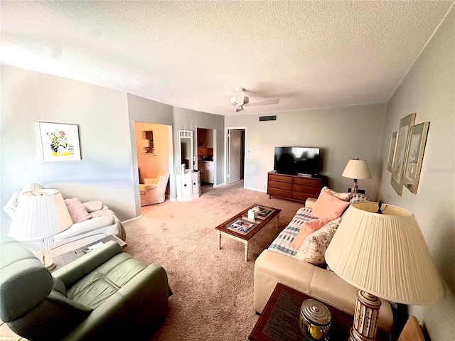 living area with a textured ceiling, ceiling fan, visible vents, and light colored carpet