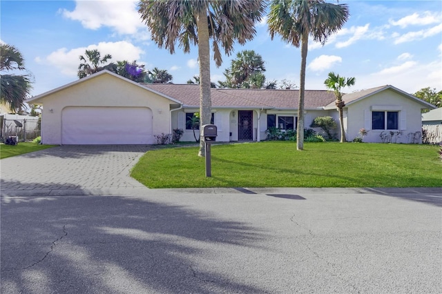 ranch-style home with a garage, fence, decorative driveway, a front lawn, and stucco siding