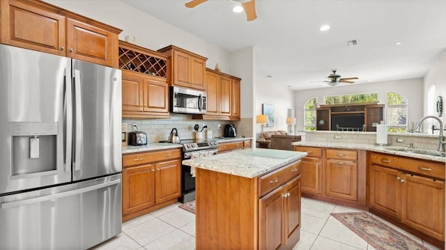 kitchen with appliances with stainless steel finishes, brown cabinets, a sink, and decorative backsplash