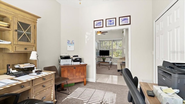 office featuring ceiling fan, light tile patterned flooring, baseboards, and light colored carpet