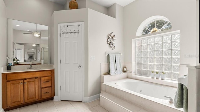 full bathroom featuring plenty of natural light, a jetted tub, vanity, and tile patterned floors