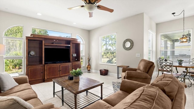 living room with a ceiling fan, a healthy amount of sunlight, baseboards, and light tile patterned floors