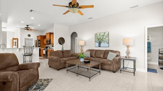 living room featuring arched walkways, light tile patterned floors, and visible vents