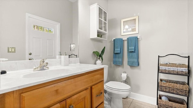 bathroom with toilet, vanity, baseboards, and tile patterned floors