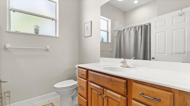 full bath with baseboards, vanity, toilet, and a healthy amount of sunlight