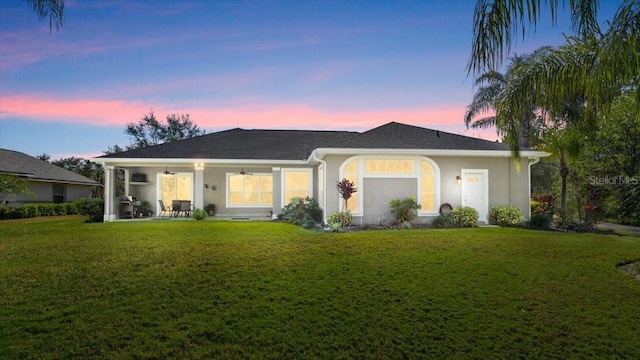 view of front facade with a front yard, a patio area, ceiling fan, and stucco siding