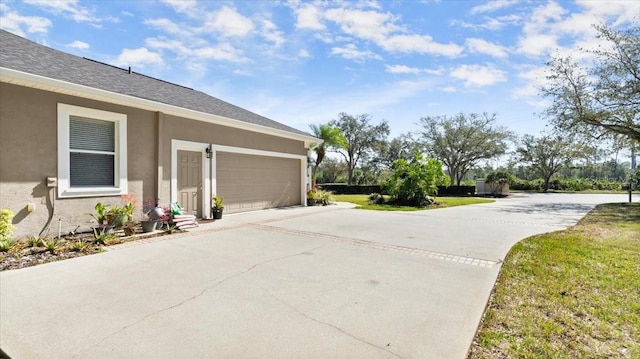 view of side of home with driveway, roof with shingles, an attached garage, and stucco siding