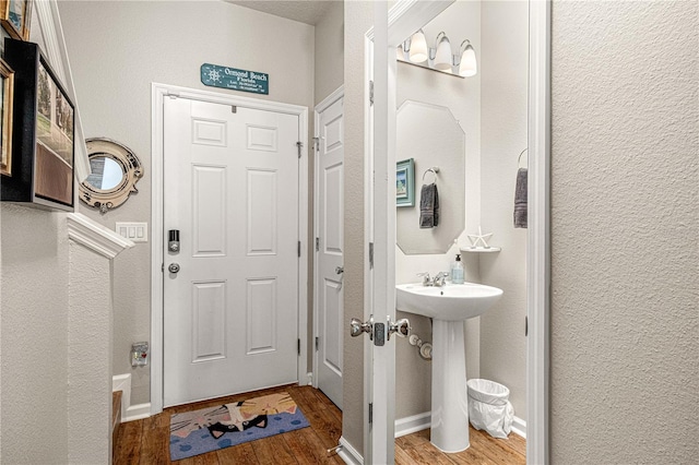 bathroom featuring a sink, a textured wall, baseboards, and wood finished floors