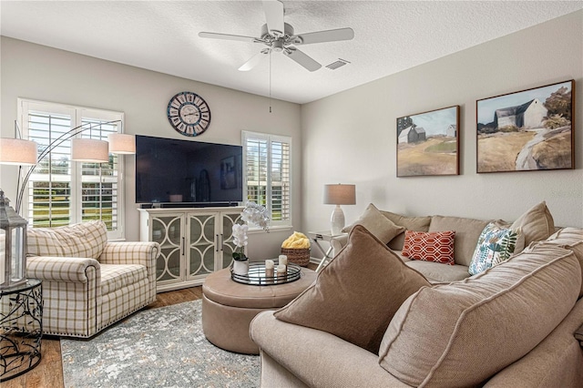 living area featuring a textured ceiling, visible vents, wood finished floors, and a ceiling fan