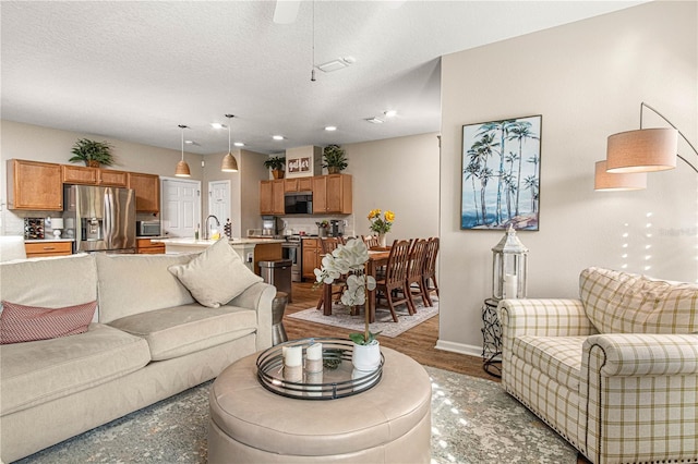 living room with a textured ceiling, recessed lighting, wood finished floors, and baseboards