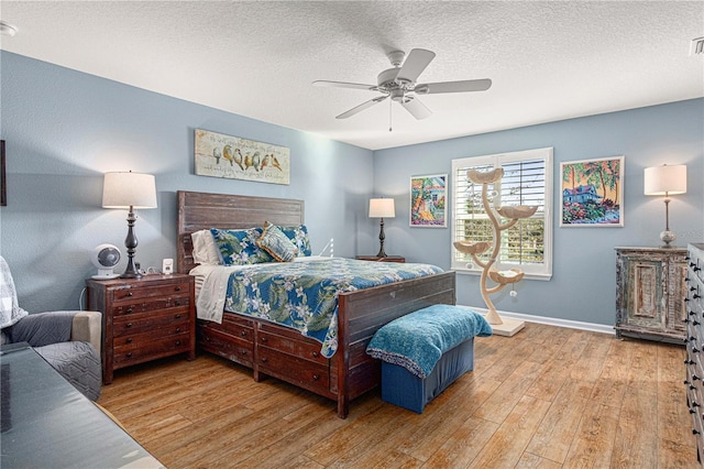 bedroom with ceiling fan, a textured ceiling, baseboards, and hardwood / wood-style flooring