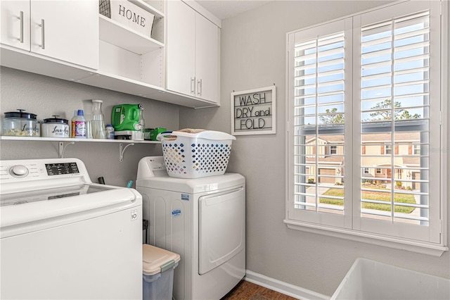 clothes washing area featuring baseboards, cabinet space, and washing machine and clothes dryer