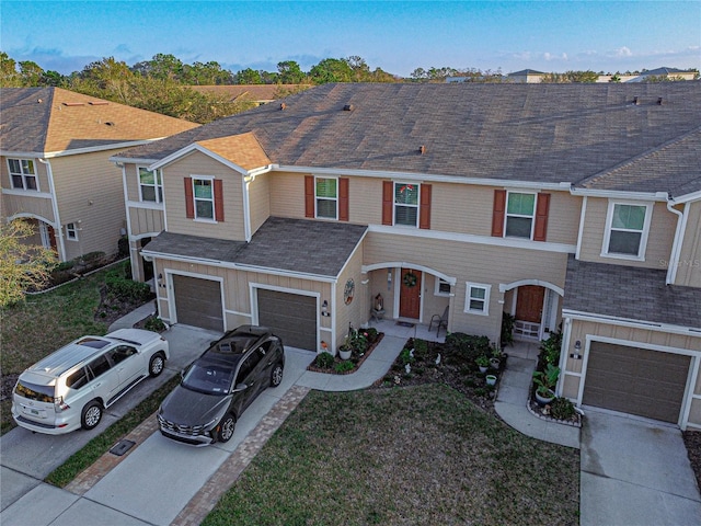 multi unit property featuring a garage, concrete driveway, a shingled roof, and board and batten siding