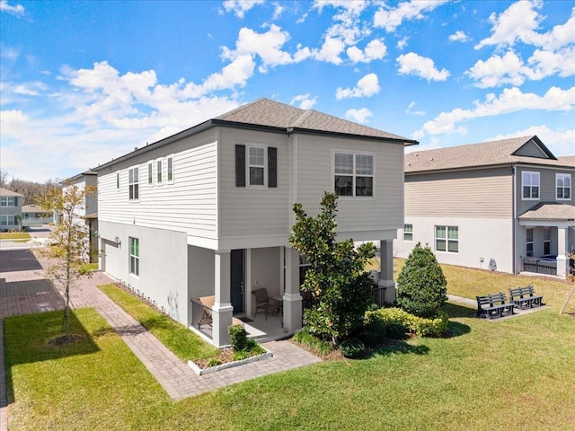 rear view of property featuring a lawn and stucco siding