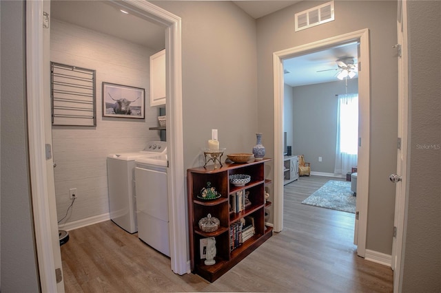 laundry area featuring cabinet space, baseboards, visible vents, washing machine and clothes dryer, and light wood-type flooring