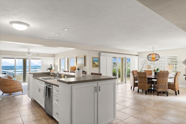 kitchen featuring white cabinets, dishwasher, an island with sink, dark countertops, and a sink