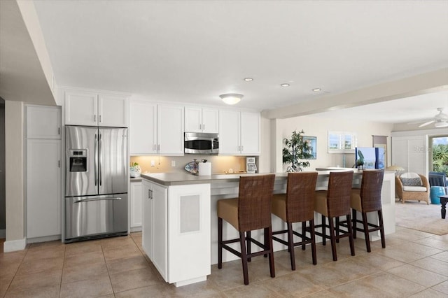 kitchen with white cabinets, a kitchen bar, stainless steel appliances, and light tile patterned flooring