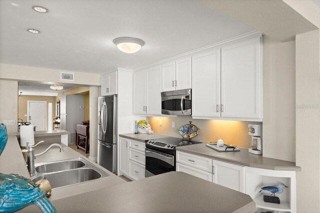 kitchen featuring appliances with stainless steel finishes, white cabinets, and a sink