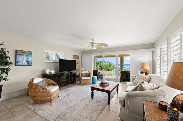 living area with light tile patterned floors, ceiling fan, and baseboards