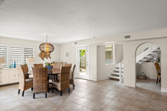 dining space featuring stairway, visible vents, and a healthy amount of sunlight