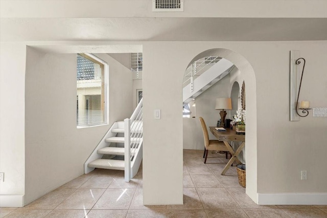 staircase with tile patterned flooring, visible vents, and arched walkways