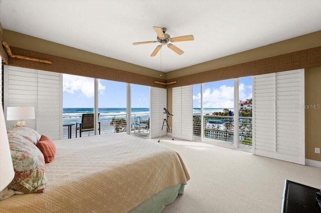 bedroom with access to outside, multiple windows, carpet, and a water view