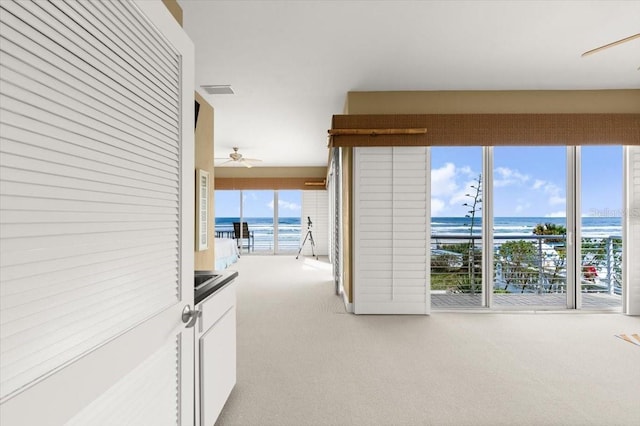 corridor with light colored carpet and a water view