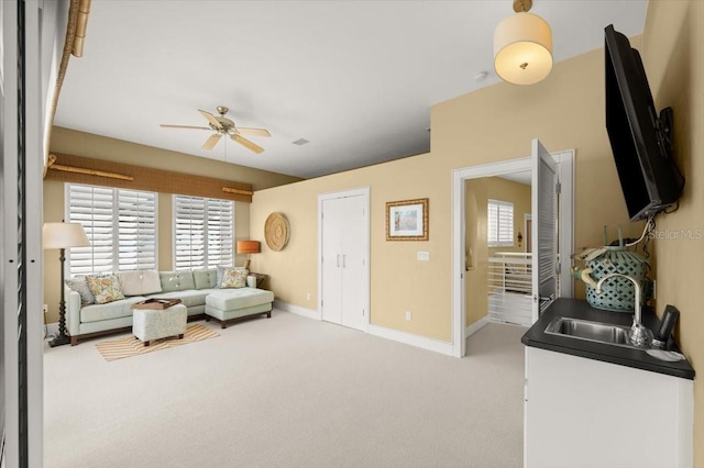 living room with a ceiling fan, carpet, and baseboards