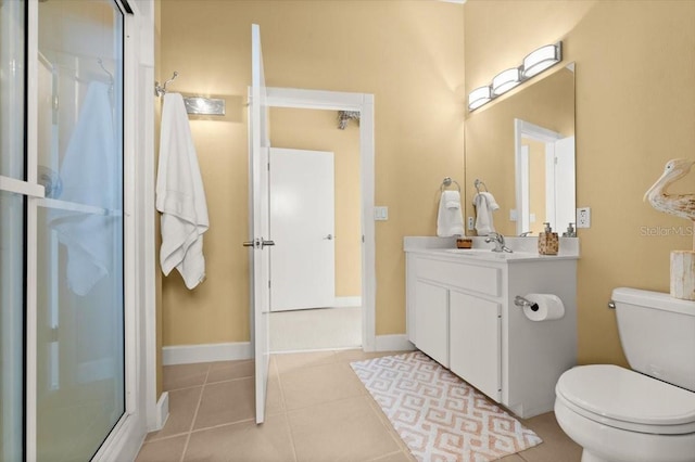 bathroom with toilet, vanity, baseboards, tile patterned floors, and a stall shower