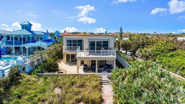 rear view of house with a balcony, a patio area, stairway, and an outdoor pool