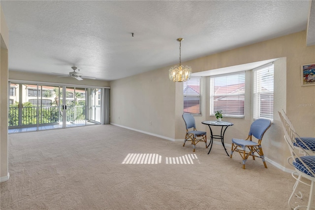 407 Bouchelle Dr Unit 205, New Smyrna Beach, FL 32169 - sitting room featuring a textured ceiling, carpet floors, ceiling fan with notable chandelier, and baseboards