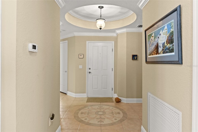 foyer with visible vents, baseboards, a tray ceiling, ornamental molding, and light tile patterned floors