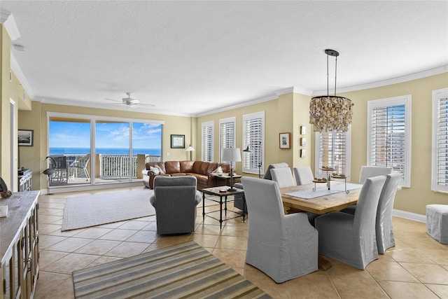 dining room with ceiling fan with notable chandelier, a textured ceiling, light tile patterned flooring, crown molding, and baseboards