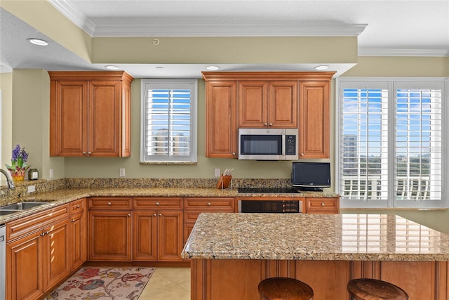 kitchen with a breakfast bar, ornamental molding, appliances with stainless steel finishes, and a sink