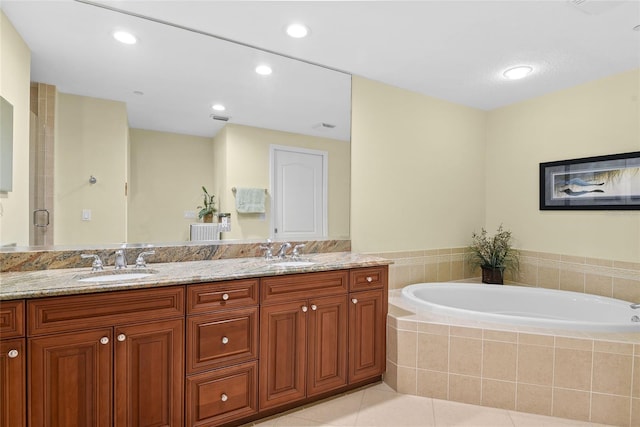 bathroom featuring tile patterned flooring, double vanity, a bath, and a sink