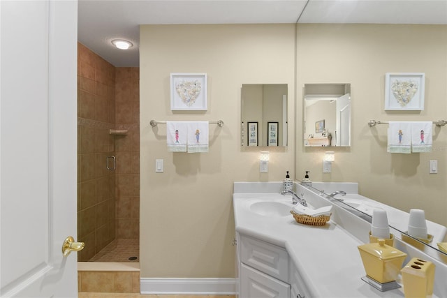 full bathroom with baseboards, vanity, and a tile shower