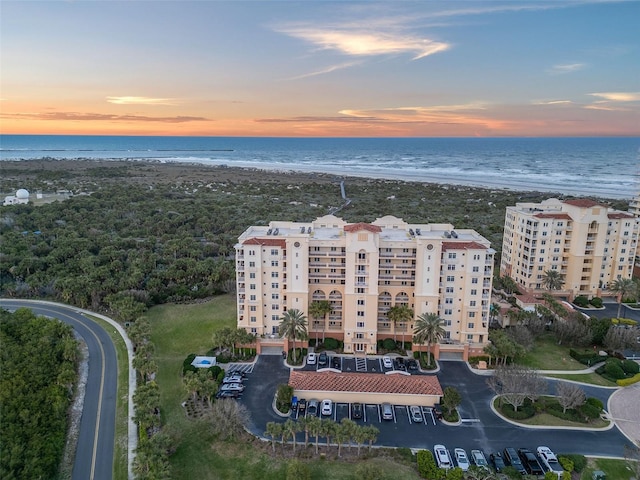 aerial view at dusk with a view of the beach and a water view