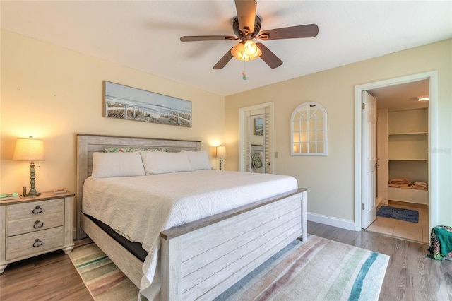 bedroom with a ceiling fan, baseboards, and wood finished floors