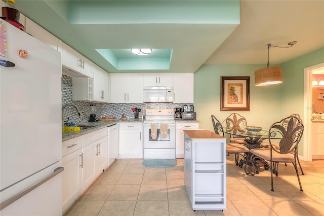 kitchen with white appliances, a tray ceiling, decorative backsplash, and a sink