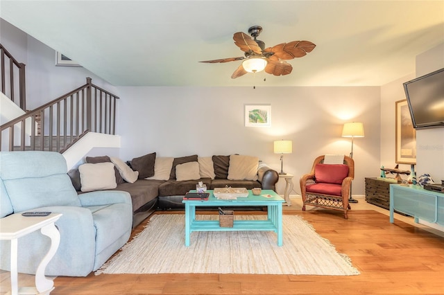 living room with light wood finished floors, baseboards, stairway, and a ceiling fan