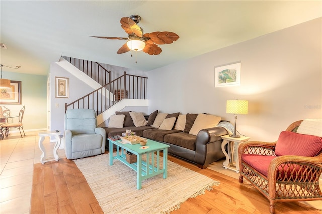 living room with visible vents, a ceiling fan, light wood-type flooring, baseboards, and stairs