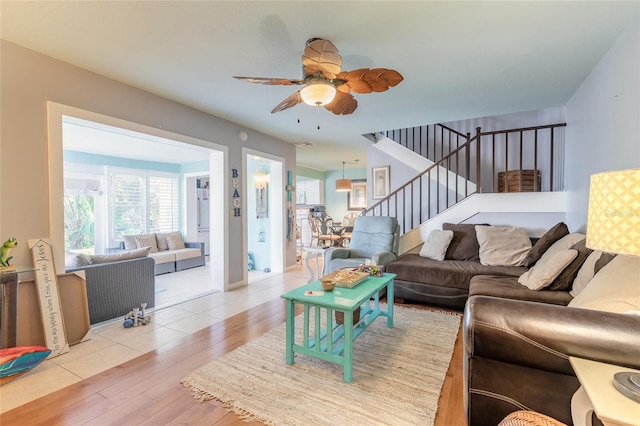 living room with ceiling fan, stairway, and light wood-style floors