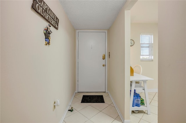 doorway to outside with light tile patterned flooring, a textured ceiling, and baseboards