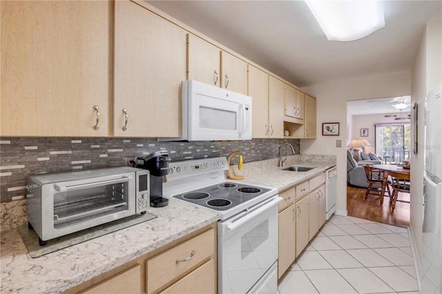 kitchen with light brown cabinets, white appliances, light tile patterned floors, and a sink