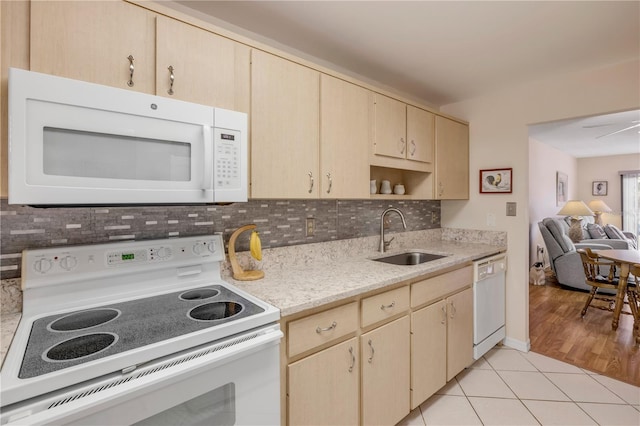 kitchen featuring light tile patterned floors, decorative backsplash, light brown cabinets, a sink, and white appliances