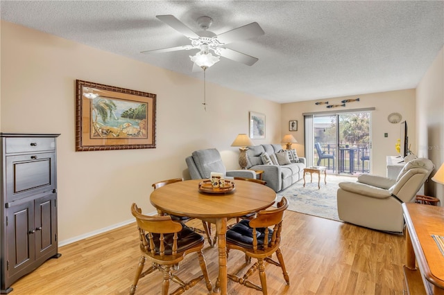 dining area featuring baseboards, ceiling fan, light wood-style flooring, and a textured ceiling