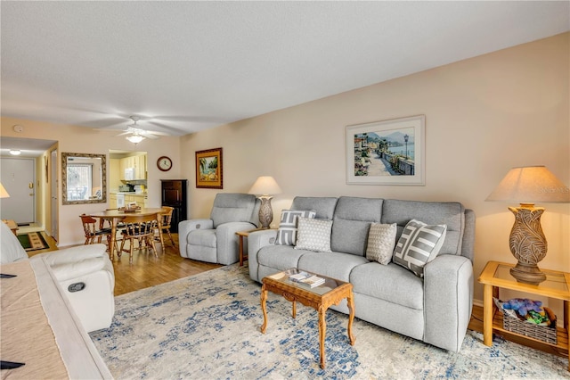 living room featuring ceiling fan, a textured ceiling, and wood finished floors