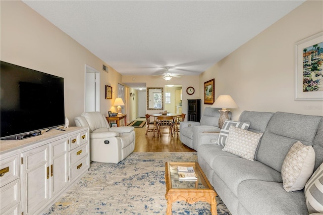 living area featuring light wood finished floors, ceiling fan, and visible vents